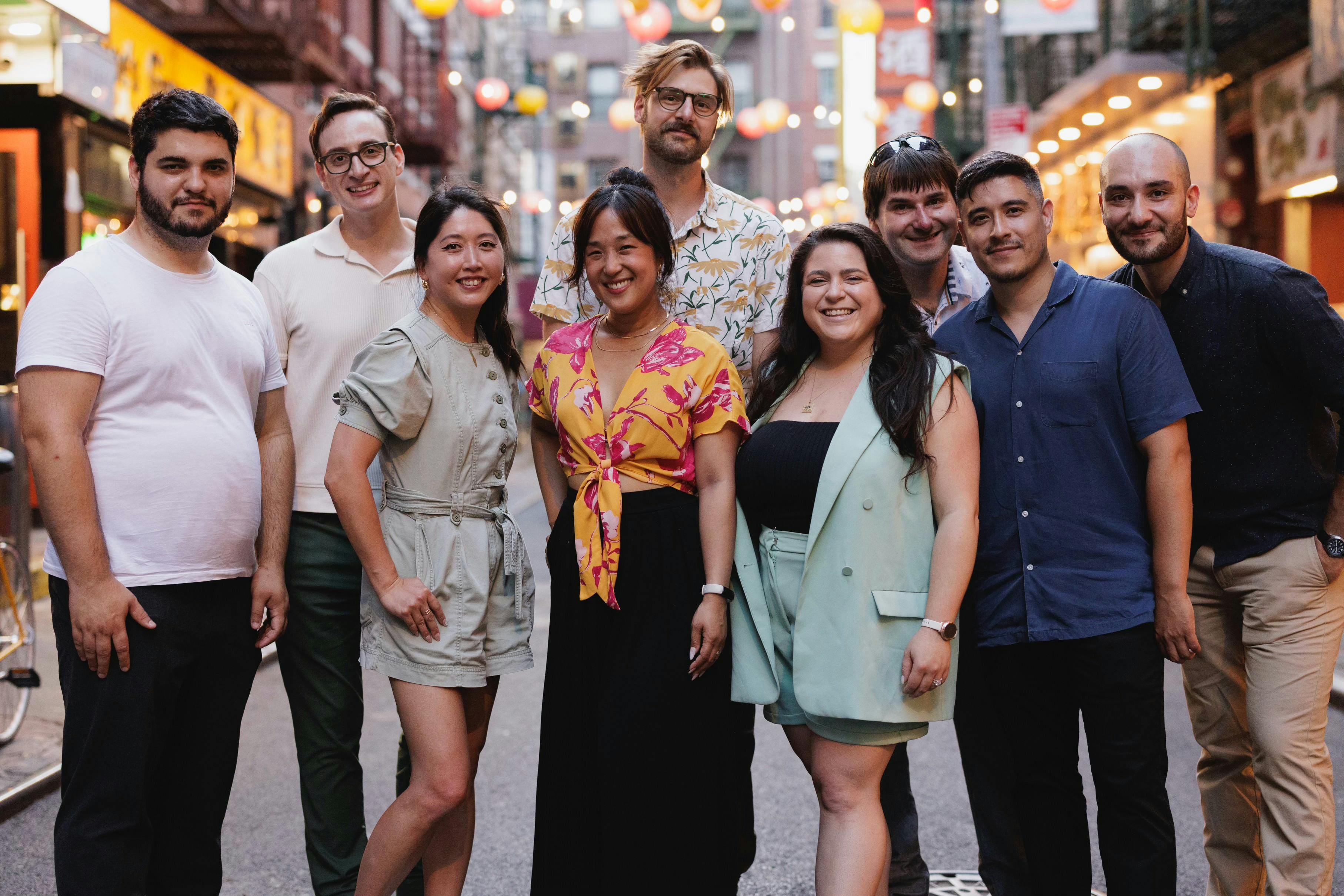 seven diverse people on a busy sidewalk.