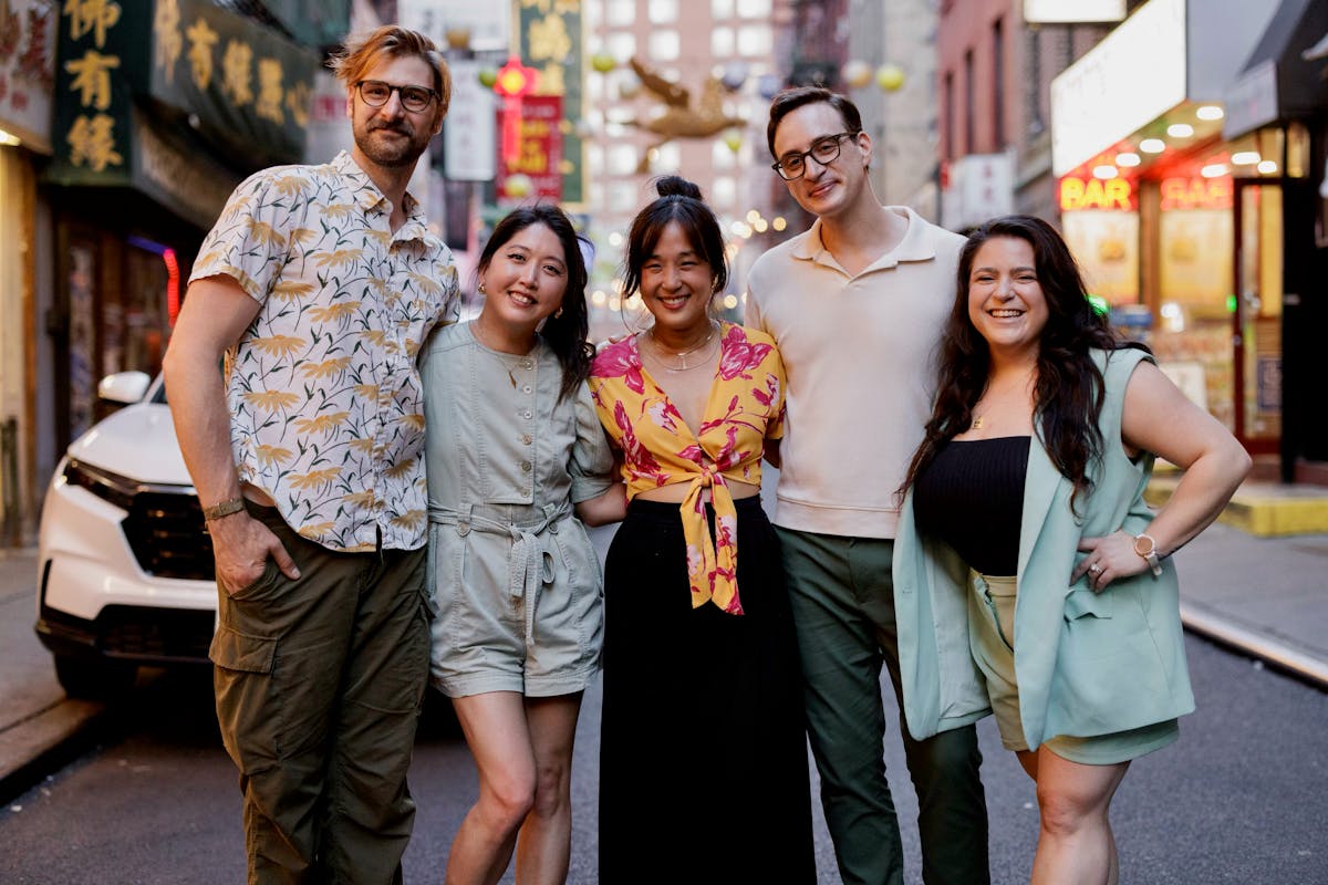 Seven diverse people on a busy sidewalk.