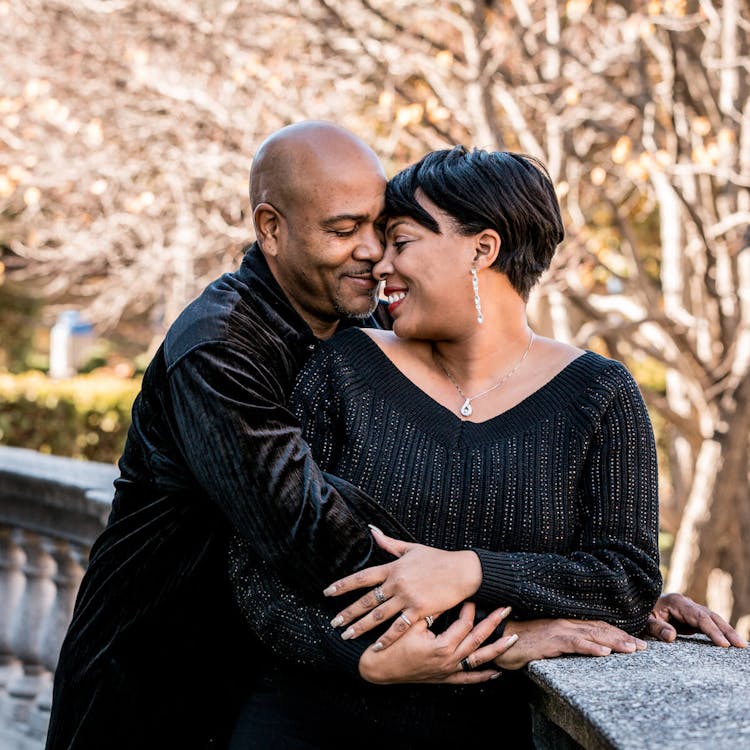 A couple embracing and smiling at each other outdoors.