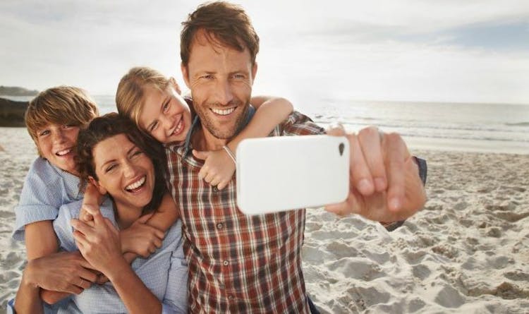 A happy family taking a selfie together on the beach.