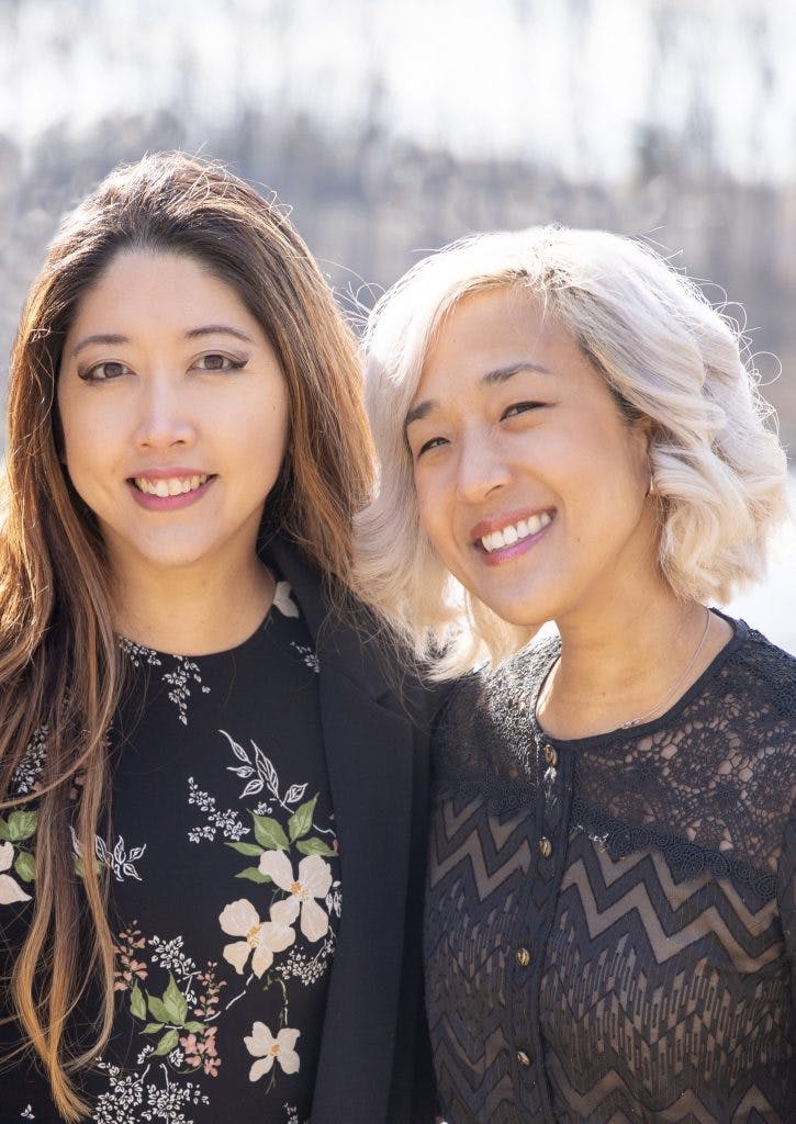 Two smiling women standing close together.