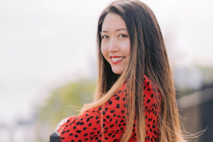 A smiling woman in a red polka dot blouse looking over her shoulder