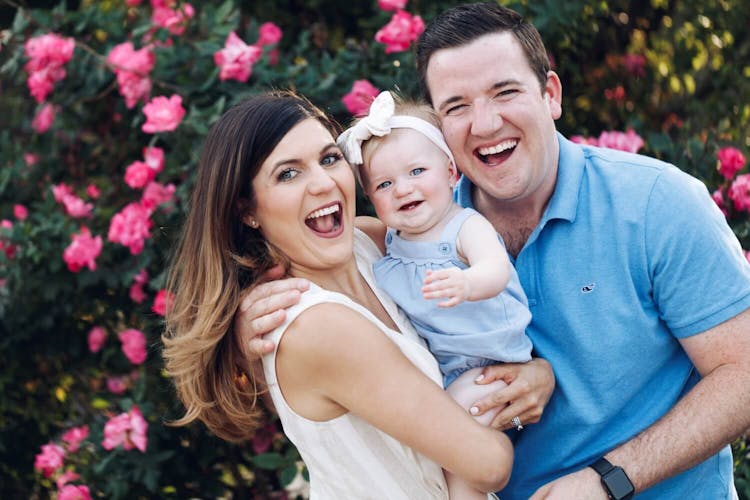 Joyful family of three with a young child smiling in a floral setting