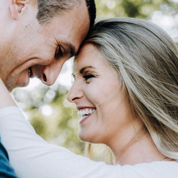 A close-up of a smiling couple touching foreheads with eyes closed