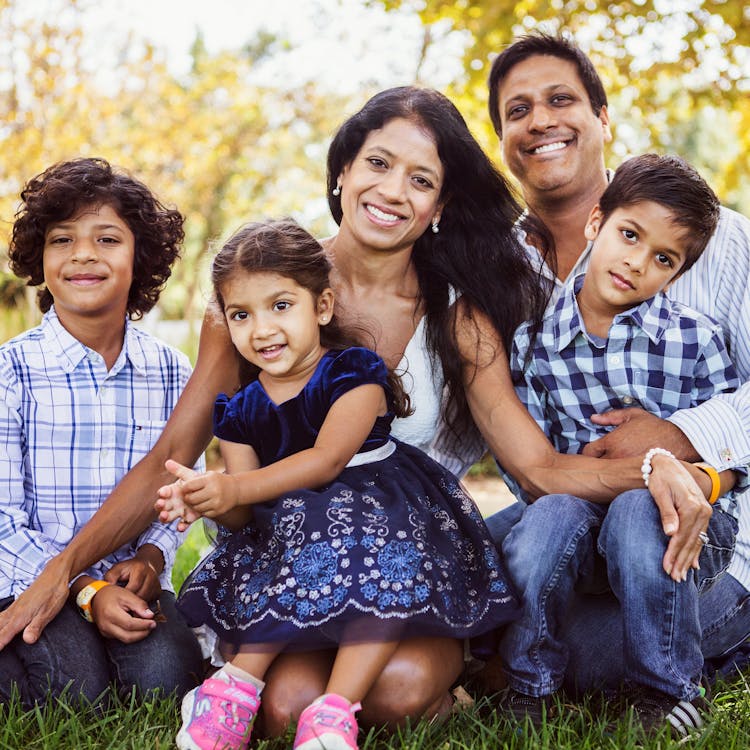 Smiling family in matching blue outfits pose for free outdoor park photoshoot