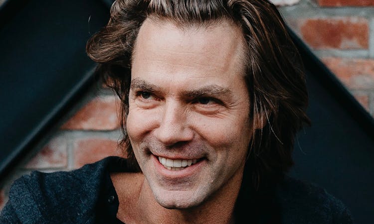 Cheerful middle-aged man with tousled hair smiling