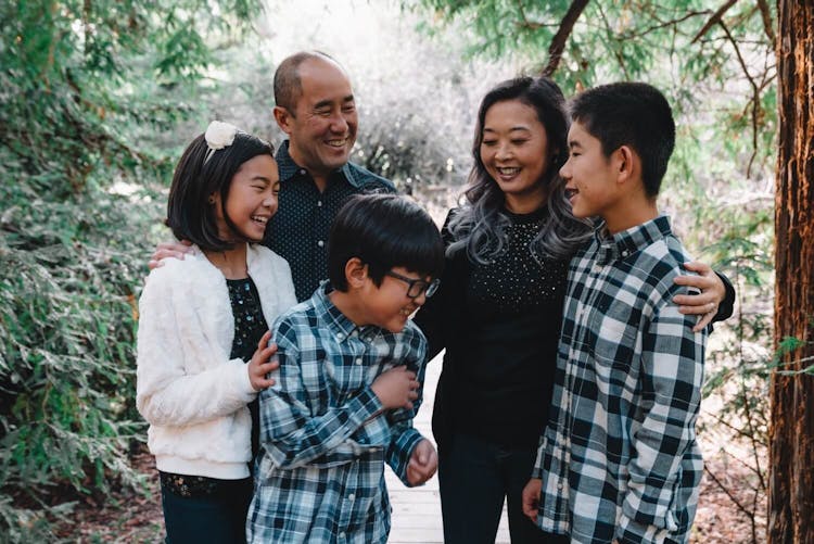 A happy family of five with three children smiling together in a forest